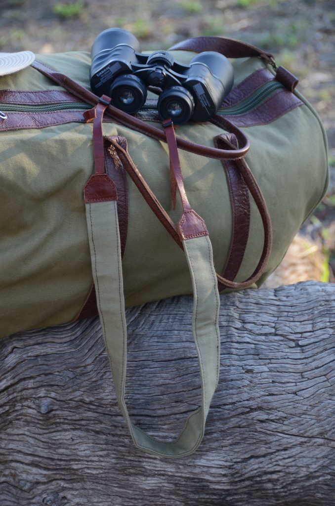 Bird Nird canvas and leather strap with binoculars on a duffel bag